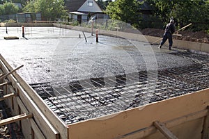 worker leveling fresh concrete slab with a special working tool