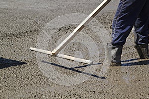 worker leveling fresh concrete slab with special working tool