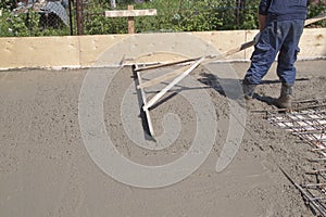 worker leveling fresh concrete slab with special working tool