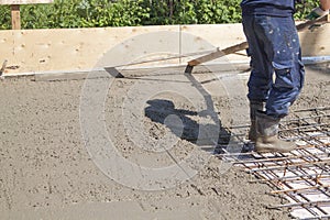 worker leveling fresh concrete slab with special working tool