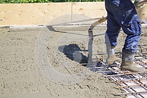 worker leveling fresh concrete slab with a special working tool