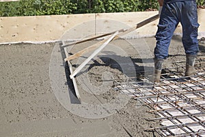 worker leveling fresh concrete slab with a special working tool