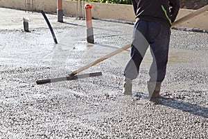 worker leveling fresh concrete slab with a special working tool