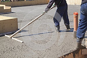 worker leveling fresh concrete slab with a special working tool