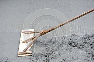 Worker leveling with trowel uneven fresh concrete at house building