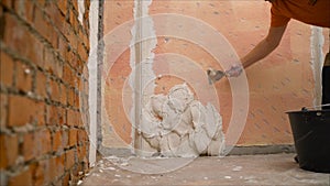 Construction notched trowel and worker hands with white mortar on wall. Worker levels a wall with mortar