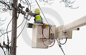 Worker in lift boom bucket by electrical pole