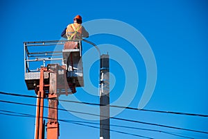 Worker in lift bucket repair light pole