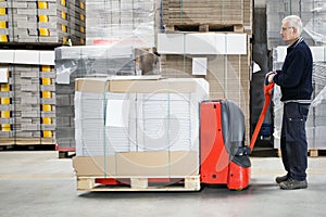 Worker With Loaded Handtruck In Warehouse photo