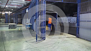 Worker on loader transports boxes in warehous. Scene. Worker standing on loader controls it to transport cargo boxes in