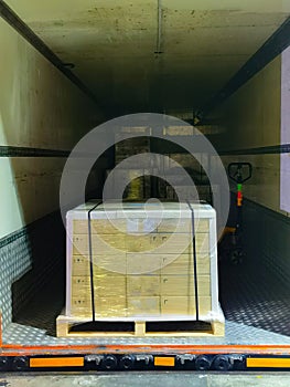 Worker loading and unloading shipment carton boxes and goods on wooden pallet by forklift  from container truck to warehouse cargo