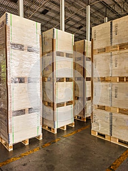 Worker loading and unloading shipment carton boxes and goods on wooden pallet by forklift from container truck to warehouse cargo