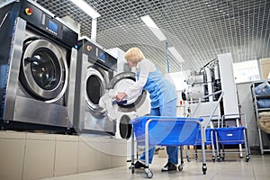 The worker loads the Laundry clothing into the washing machine photo