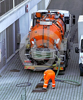 Worker lowers sewer hose into sewer pit