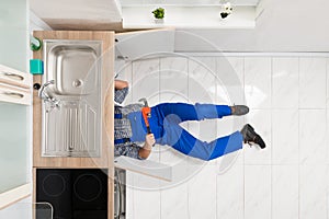 Worker Lying On Floor Repairing Sink