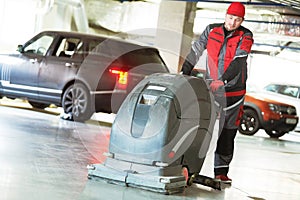 Worker with machine cleaning floor in parking garage.