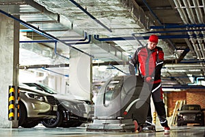 Worker with machine cleaning floor in parking garage.