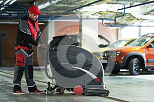 Worker with machine cleaning floor in parking garage.