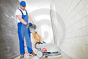 worker with machine cleaning floor in residence hall