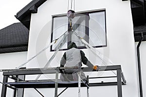 The worker maintains a crane at a construction site. The crane lifts the metal structure. The cargo is lifted into the