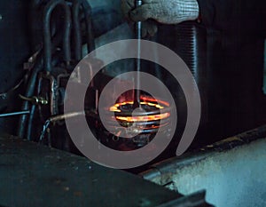 The worker makes hardening heat treatment of the metal gear on a special machine, close-up, hardening of metal, quenching