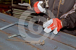 The worker makes a mark on a metal surface. Drilling holes in metal profiles for mounting metal structures.