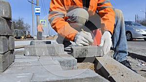 A worker makes a marking on a concrete block, lays a tile.