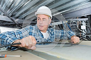 Worker making mounting for electric cable in ceiling