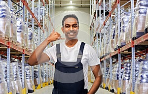 Worker making phone call gesture at warehouse