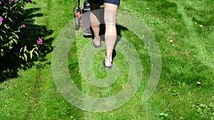 Worker male man shorts flip-flop shoes mow lawn grass in yard