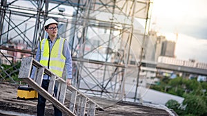 Worker man carrying aluminium ladder and tool box