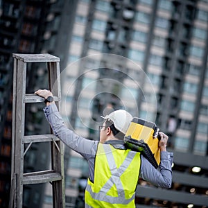 Worker man carrying aluminium ladder and tool box