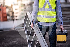 Worker man carrying aluminium ladder and tool box