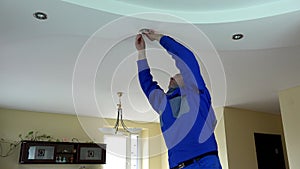 Worker man change LED light bulb in ceiling in client room. 4K