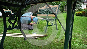 Worker man disassemble retro bench in parts. Outdoor furniture renew process