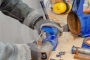 Worker man dismantles old metal vice in workshop