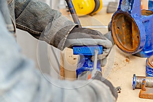 Worker man dismantles old metal vice in workshop