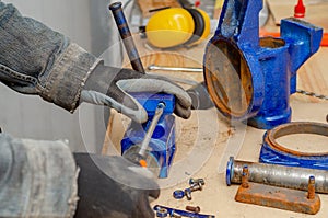 Worker man dismantles old metal vice in workshop