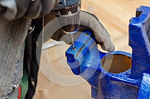 Worker man dismantles old metal vice in workshop