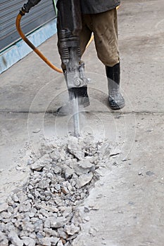 Worker man drilling cement concrete road