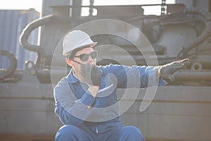 Worker man in hardhat and safety vest holding laptop and Female foreman talks on two-way radio control loading containers box from