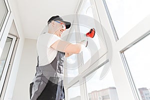 Worker man installs plastic windows and doors with double-glazed white