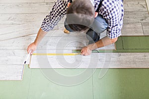 Worker Man laying laminate flooring at home room