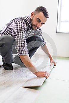 Worker Man laying laminate flooring at home room