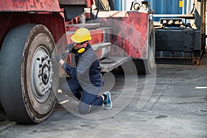 Worker man operate checking and fix the wheels forklift crane at container cargo harbor