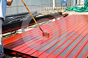 worker man paint rustproof with channels steel for building structure house roof. professional use equipment on iron surface