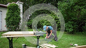 Worker man renewing outdoor furniture frames with grinder