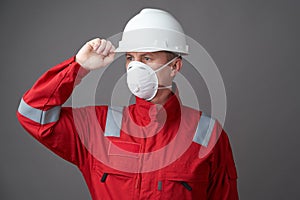 Worker man wearing hygienic mask, overall and protective hard hat