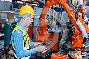 Worker man working with robot arm automate welding machine in modern metal factory. Engineer program robotic in heavy industry