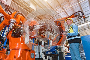 Worker man working with robot arm automate welding machine in modern metal factory. Engineer program robotic in heavy industry photo